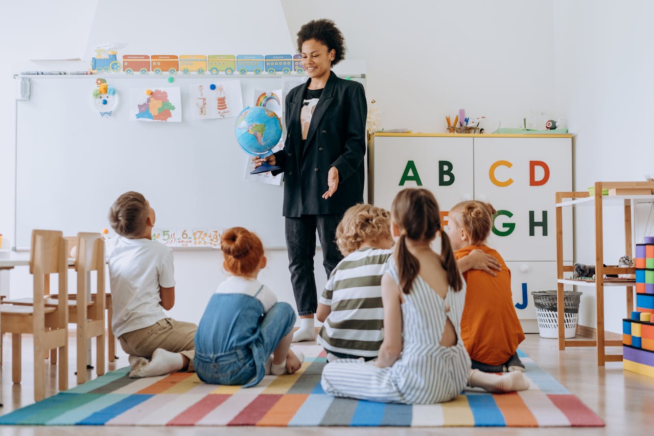 Teacher interacts with a group of young students in a vibrant classroom setting, using a globe for educational activities.